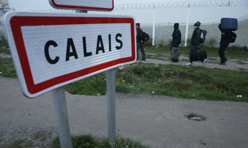 Varios inmigrantes cargan con sus pertenencias durante la evacuación de la 'Jungla' de Calais. REUTERS/Pascal Rossignol