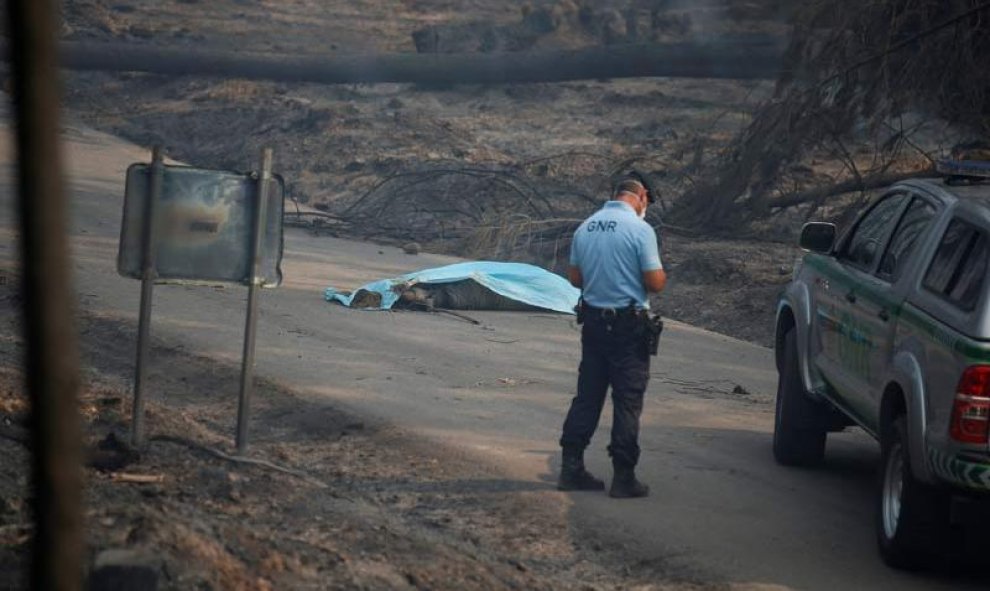 Un miembro de la Guardia Nacional republicana observa a una de las víctimas mortales del incendio, cerca de Pedrogao Grande. | RAFAEL MARCHANTE (REUTERS)