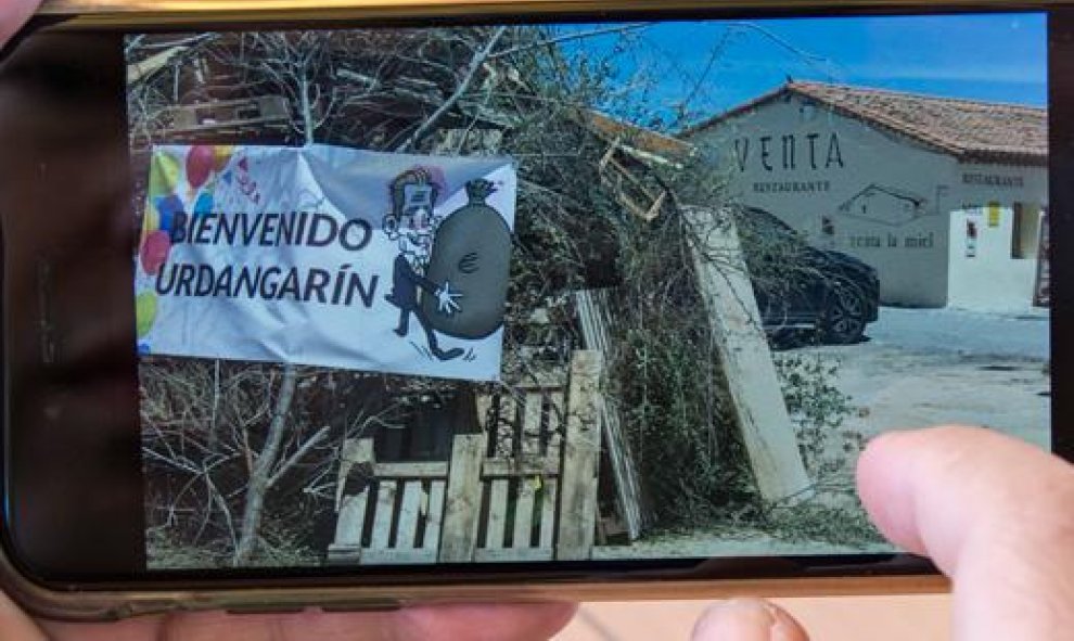 Un vecino muestra una hoguera de San Juan con una pancarta que da la bienvenida a Urdangarin. / REPORTAJE GRÁFICO: J. GÓMEZ