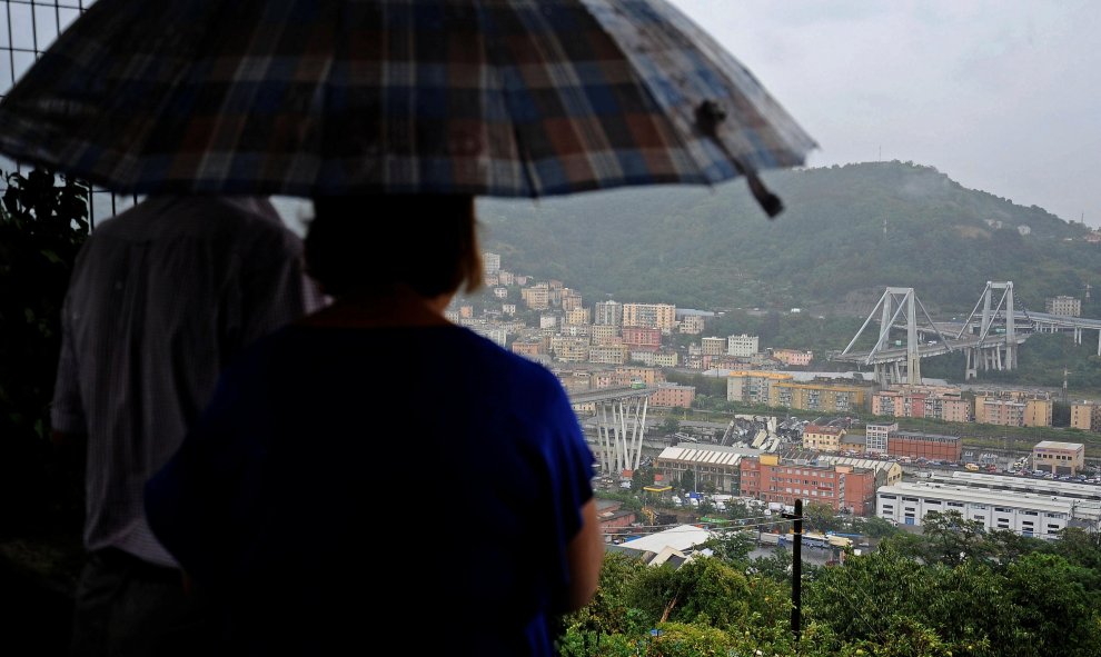 Una pareja observa el puente de Morandi tras el accidente. / REUTERS