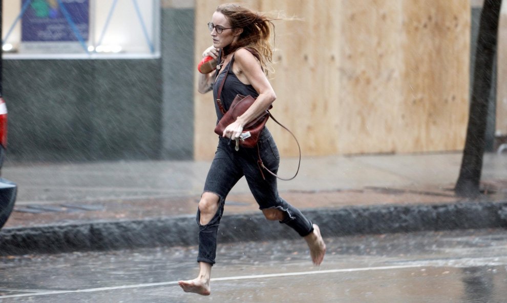 Una mujer corre en el momento del inicio de las lluvias en Wilmington (Carolina del Norte) - REUTERS/Jonathan Drake