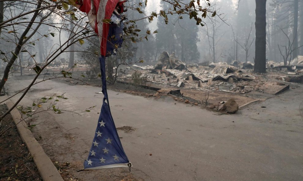 Una bandera estadounidense hecha jirones cuelga cerca de una de las casas destruidas en Camp Fire, Paradise.- REUTERS