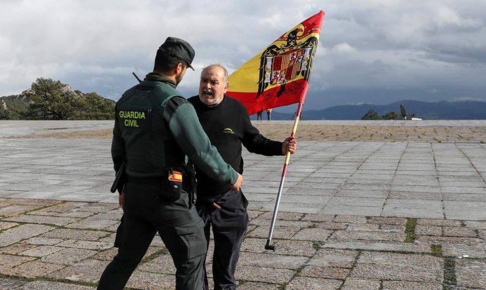 Un hombre con una bandera fascista forcejea con un Guardia Civil. (SUSANA VERA | REUTERS)