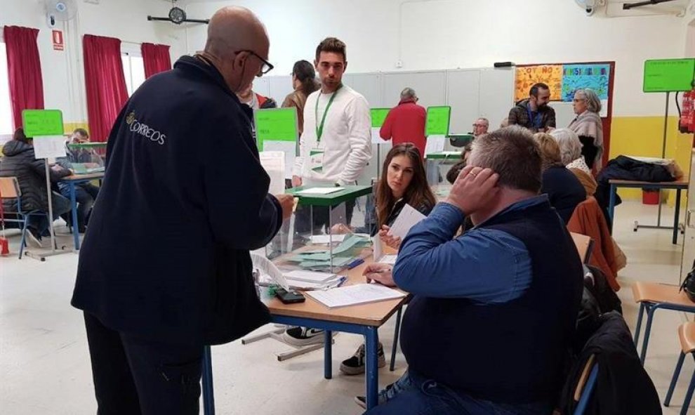 02/12/2018.- Un funcionario entrega votos que han llegado por correos y deben estar en la mesa electoral hasta que se abran, en el colegio Sor Ángela de la Cruz del distrito Macarena, en Sevilla, hoy en la jornada de los undécimos comicios autonómicos and