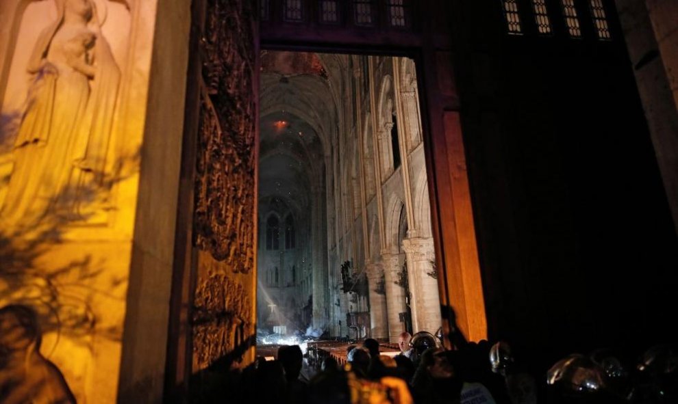 Los bomberos trabajando en el interior de la catedral. / REUTERS