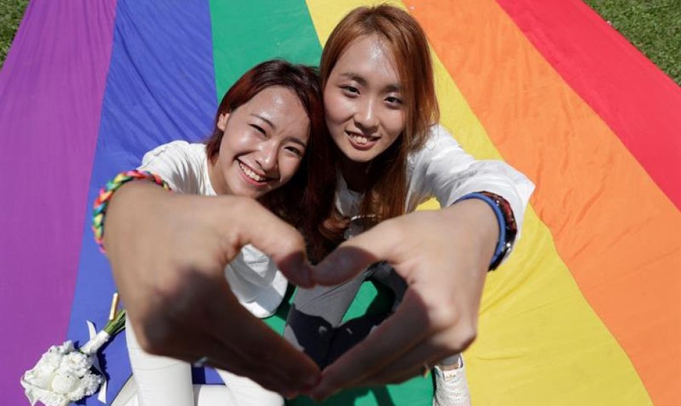 23/05/2019.- Una pareja de mujeres recién casada posa sobre una bandera LGBTI durante el primer día del registro civil para matrimonios del mismo sexo este jueves, en Taipei (Taiwán). Taiwán se convirtió en el primer país asiático en legalizar el matrimon