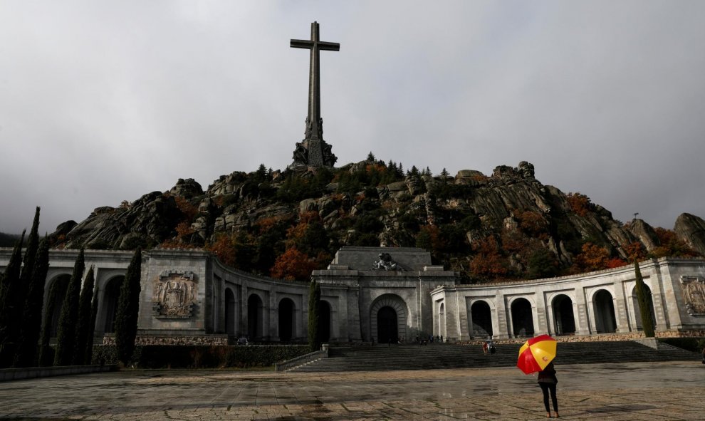 20/10/2019.- Una mujer sostiene un paraguas en el Valle de los Caídos, el mausoleo que contiene los restos del ex dictador Francisco Franco. / REUTERS (Susana Vera)
