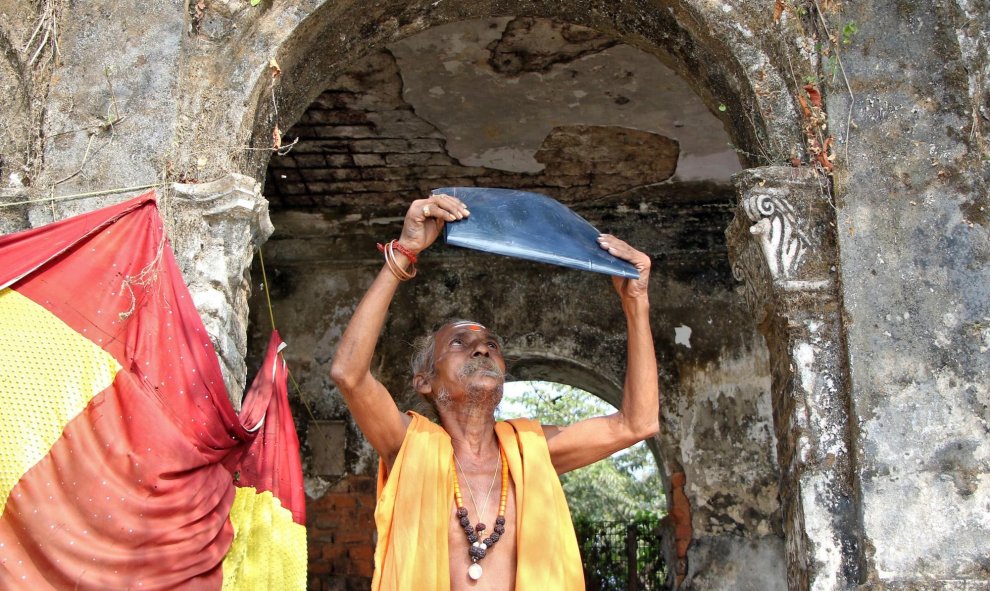 26/12/2019 - Un sacerdote hindú observa el eclipse a través de una película de rayos X fuera de un templo en Agartala, India. REUTERS / Jayanta Dey