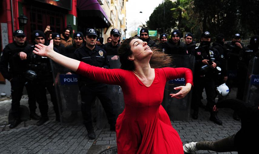 Una mujer baila ante la policía antidisturbios durante una protesta contra el desalojo de un edificio ocupado en Estambul. // OZAN KOSE (AFP)