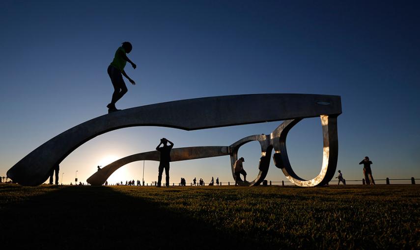 Unos jóvenes sobre una escultura en forma de gafas gigantes, en Ciudad del Cabo (Suráfrica). // MIKE HUTCHINGS (REUTERS)
