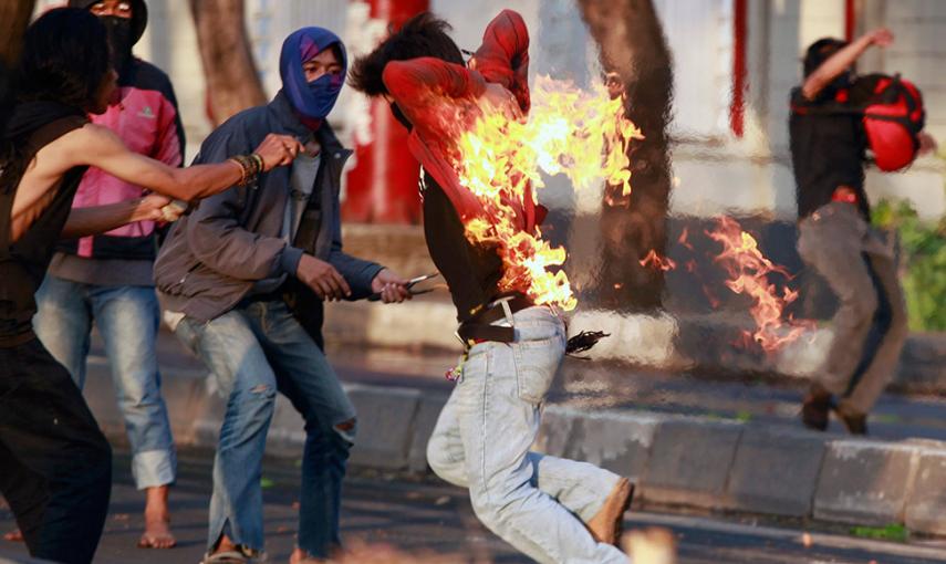Un manifestante indonesio corre tras ser alcanzado por el fuego mientras lanzaba un cóctel molotov a la policía durante una protesta por el incremento de los precios del combustible. // AHMAD YUSUF (REUTERS)
