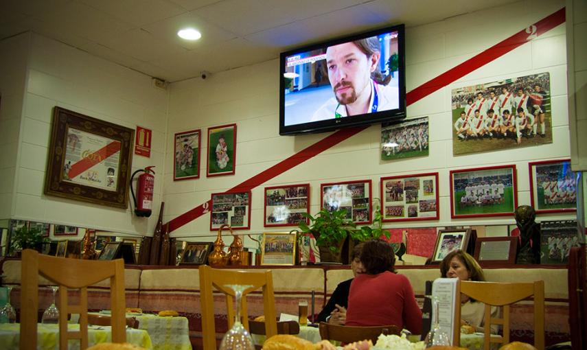 Los comensales del restaurante Cota, bajo una pantalla de televisión con el líder de Podemos -también de Vallecas- en las noticias. // CHRISTIAN GONZÁLEZ