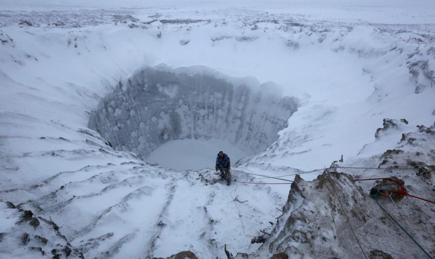 Un miembro de una expedición, en el borde de un cráter recién formado en la península de Yamal, en el norte de Siberia. // VLADIMIR PUSHKAREV (REUTERS)