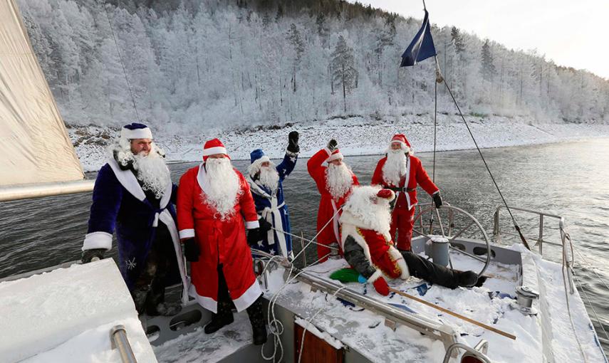 Los miembros de un club náutico vestidos de Papá Noël, saludan a la tripulación de otro barco. // LLYA NAYMUSHIN (REUTERS)