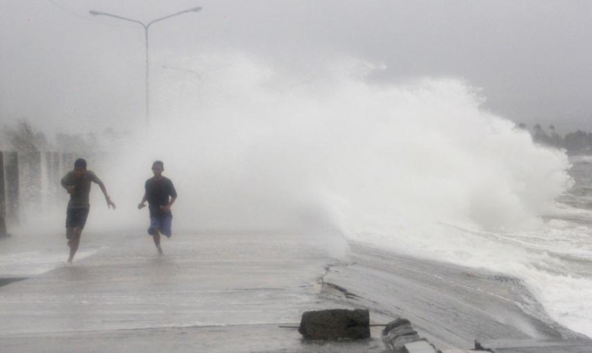 Un par de personas corren para evitar las olas provocadas por el tfón Hagupit, en la ciudad de Legazpi, en la provincia filipina de Albay. // EFE/EPA/ZALRIAN Z. SAYAT