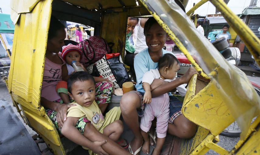 Una familia en su triciclo hacia un centro de evacuación en Manila. // EFE/EPA/DENNIS M. SABANGAN