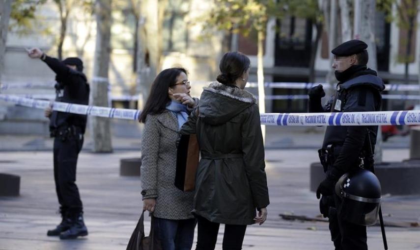 Un agente de Policía Nacional informa a dos ciudadanas en los alrededores de la calle Génova de Madrid. /EFE