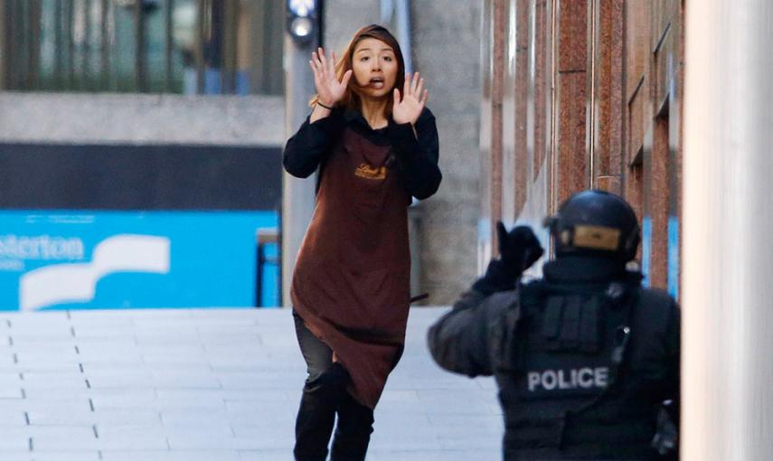 Una rehén corre hacia un oficial de policía, durante el secuestro de una cafetería en el centro de Sidney. /JASON REED (REUTERS)