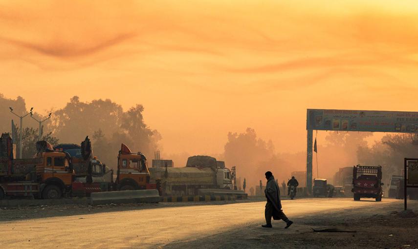 La luz de la salida del sol ilumina el humo en el aire, mientras un hombre cruza la calle cerca de la Base de Operaciones Fenty en la provincia de Nangarhar de Afganistán. /LUCAS JACKSON (REUTERS)