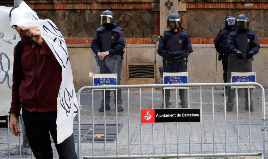 Un manifestante se cubre la cara con una pancarta delante de los policías que vigilaban un edificio del Gobierno, durante una protesta contra la nueva ley de seguridad ciudadana en Barcelona. - REUTERS/Gustau Nacarino