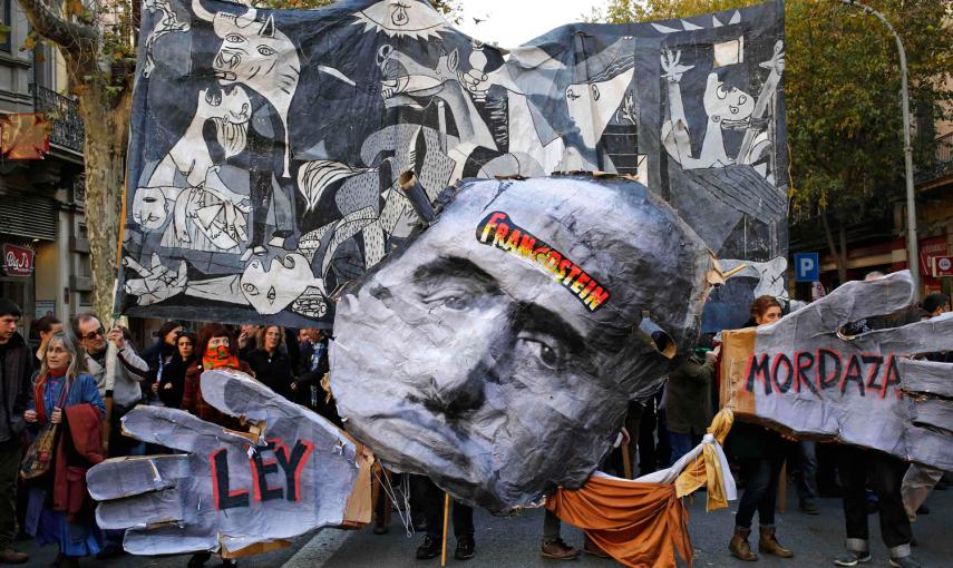 Los manifestantes sostienen una pancarta con el Guernika de Picaso y una caricatura de Franco durante una protesta contra la nueva ley de seguridad ciudadana en Barcelona. - REUTERS