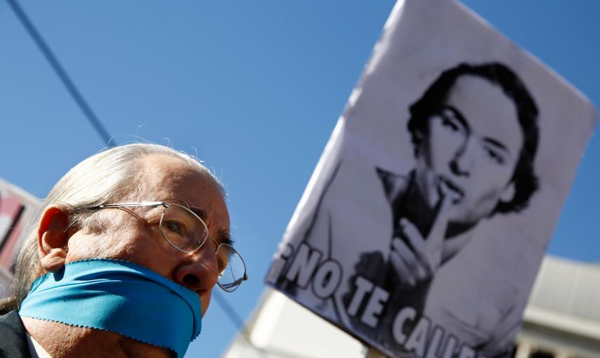 Un hombre, con la boca amordazada, se encuentra bajo un cartel que dice "No te calles" durante una protesta contra la nueva ley de seguridad ciudadana en Madrid. REUTERS