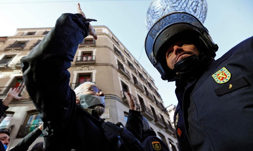 Un hombre, con la boca tapada, se enfrenta con un policía antidisturbios durante una protesta contra la nueva ley de seguridad anti-protesta del gobierno español en Madrid. -REUTERS