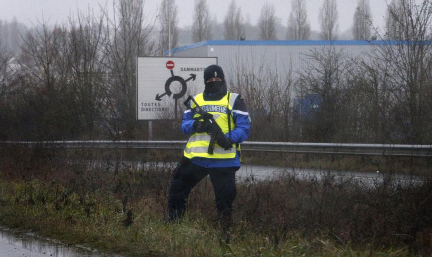 Un agente de policía vigila una carretera cercana a la zona industrial en Dammartin-en-Goele (noroeste de París), donde los sospechosos de la masacre de "Charlie Hebdo" se han refugiado con rehenes.-EFE