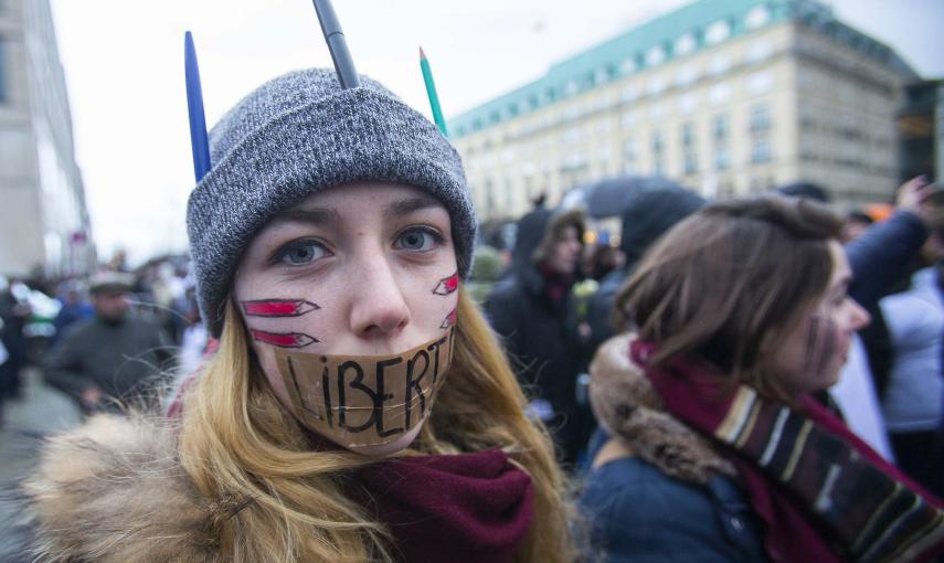 A woman wears a tape with the word 'Liberte' (Freedom) on her mouth during a silent protest for the victims of the shooting at the Paris offices of weekly newspaper Charlie Hebdo, at the Pariser Platz square in Berlin January 11, 2015. REUTERS/Hannibal Ha