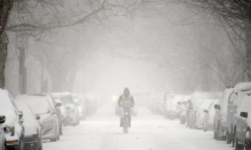 Un hombre pasa en bicicleta por una calle llena de nieve en Brooklyn. EFE/JUSTIN LANE