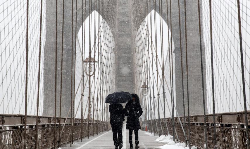 Dos personas caminan bajo la nieve por el puente de Brooklyn. EFE/ANDREW KELLY