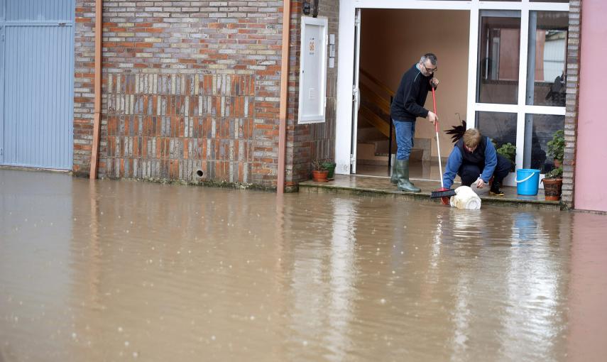 Vecinos de la localidadad cantabra de Ampuero intentan que la lluvia no entre en su domicilio tras las lluvias que han desbordado el rio Ason a su paso por el pueblo. EFE/Pedro Puente Hoyos