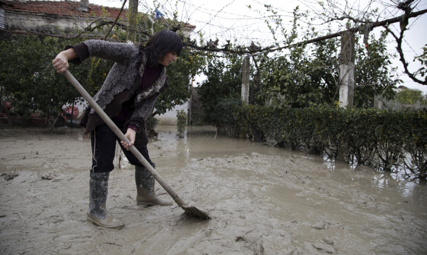 Una mujer quita lodo con una pala después de que su casa resultara inundada por la lluvia. /EFE