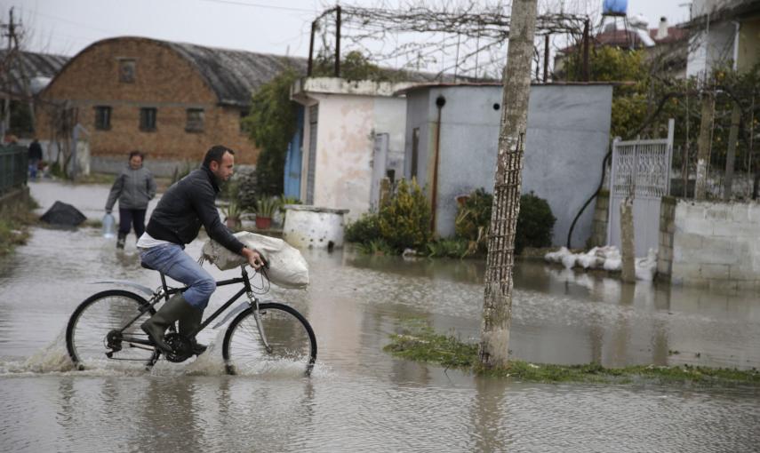 Un hombre monta en bicicleta por una calle inundada. /EFE