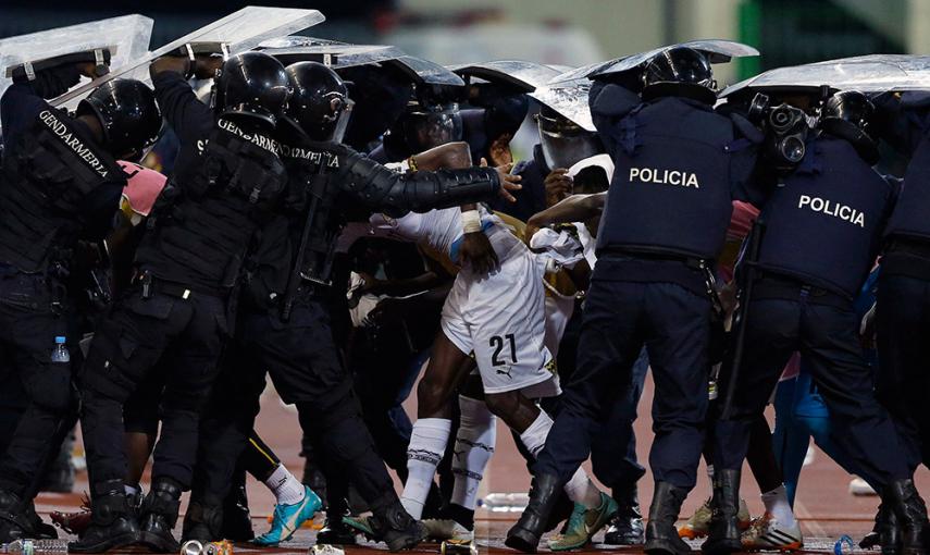 Policías antidisturbios protegen al jugador de Ghana John Boye de los objetos lanzados por los fans de Guinea Ecuatorial, en un partido de la Copa Africana de Naciones. /AMR ABDALLAH DALSH (REUTERS)