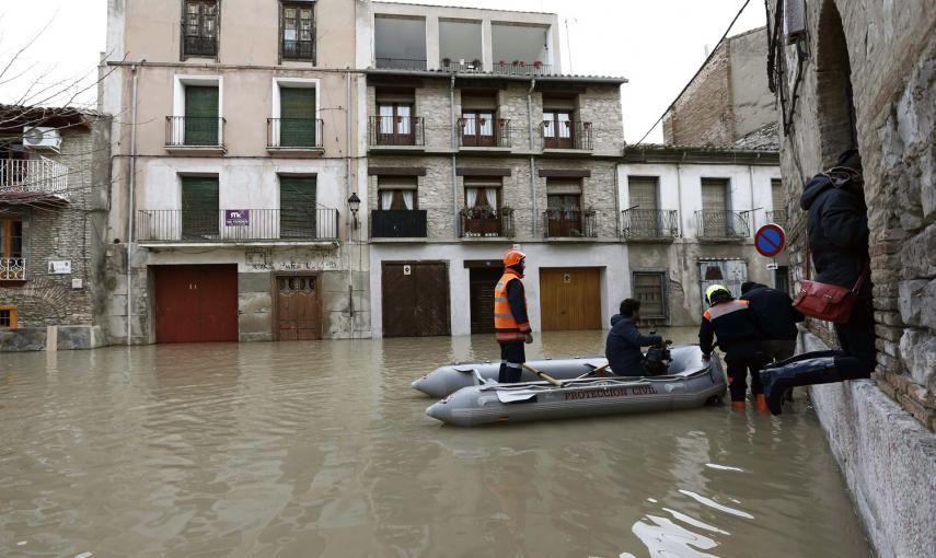 Miembros de Proteccion Civil ayudan a varias personas en el Casco Viejo de Tudela, coincidiendo con la máxima crecida del Rio Ebro, donde se han inundado las calles de la ciudad. /Jesús Diges (EFE)