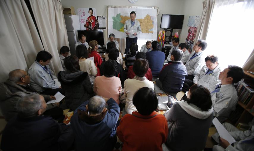 Personas que fueron evacuadas de Okuma, ciudad dentro de la zona de exclusión junto a la planta de TEPCO, asisten a una reunión con su alcalde Toshitsuna Watanabe, en el complejo temporal de viviendas que habitan en Aizuwakamatsu./ REUTERS-Toru Hanai