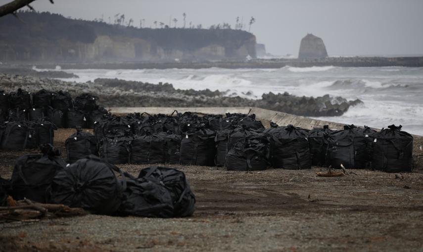 Grandes bolsas de plástico que contienen restos de tierra, hojas y desechos contaminados, son depositados en las costa devastada por el tsunami en Tomioka, provincia de Fukushima./ REUTERS-Toru Hanai