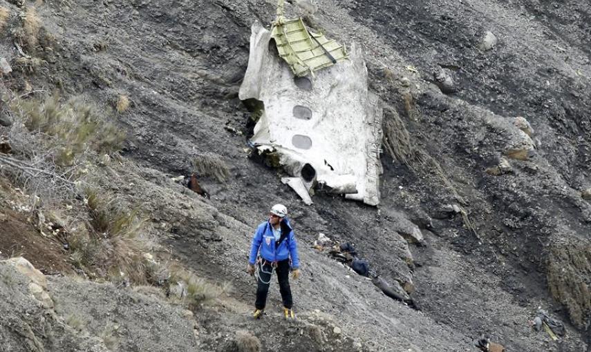 Un miembro de los servicios de rescate camina al lado del mayor un tramo de fuselaje del avión siniestrado, en el que se aprecian tres ventanillas, entre millones de fragmentos del aparato esparcidas por una amplia área de alta montaña en los Alpes franc