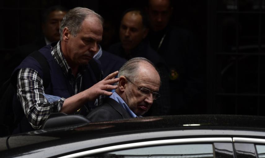 Un agente introduce a Rodrigo Rato en un coche policial. - AFP