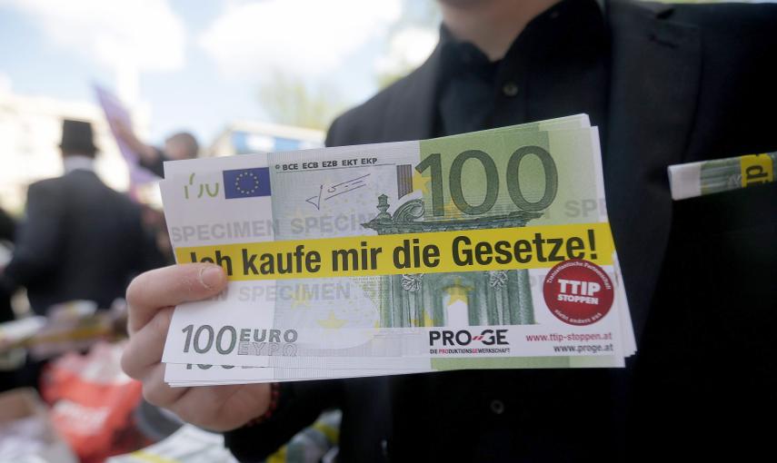Billetes falsos de 100 euros, con la frase 'Comprame la ley' escrita, en la marcha de Viena contra el TTIP. EFE/EPA/GEORG HOCHMUTH