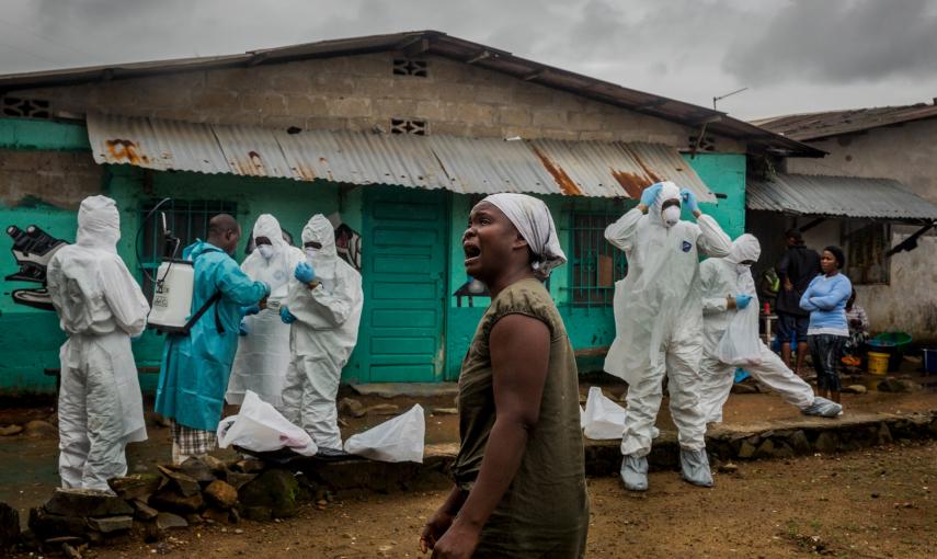 Una mujer observa como un equipo de la Cruz Roja se prepara para retirar el cuerpo de Ofori Gweah , que murió bajo síntomas de Ébola, en una zona junto al río llamado Rock Spring Valley en Monrovia central, Liberia./REUTERS/Daniel Berehulak/The New York T