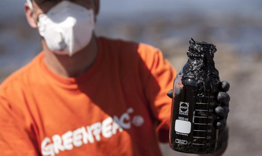 Un miembro de Greenpeace enseña un bote con muestras del combustible que ha llegado en las últimas horas a la playa de Venegueras, en el municipio grancanario de Mogán, que se cree que procede del pesquero ruso hundido Oleg Naydenov. EFE