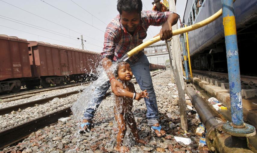 Un pasajero baña a un niño con una tubería, en un caluroso día en la ciudad de Allahabad, en el norte de India.- JITENDRA PRAKAS (REUTERS)