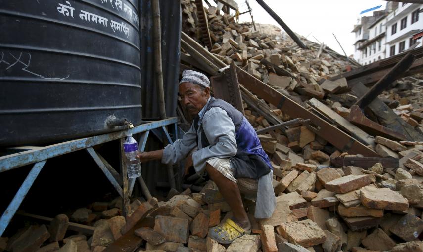 Un hombre llena una botella de agua entre los escombros. REUTERS / Navesh Chitrakar