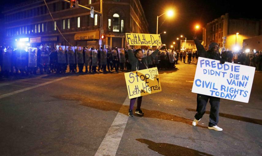 Protesters hold up signs in front of a line of police in Baltimore, Maryland. REUTERS/Jim Bourg