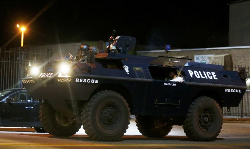 A police armoured car moves down a street as clouds of smoke and crowd control agents rise shortly after the deadline for a city-wide curfew passed in Baltimore, Maryland. REUTERS/Jim Bourg