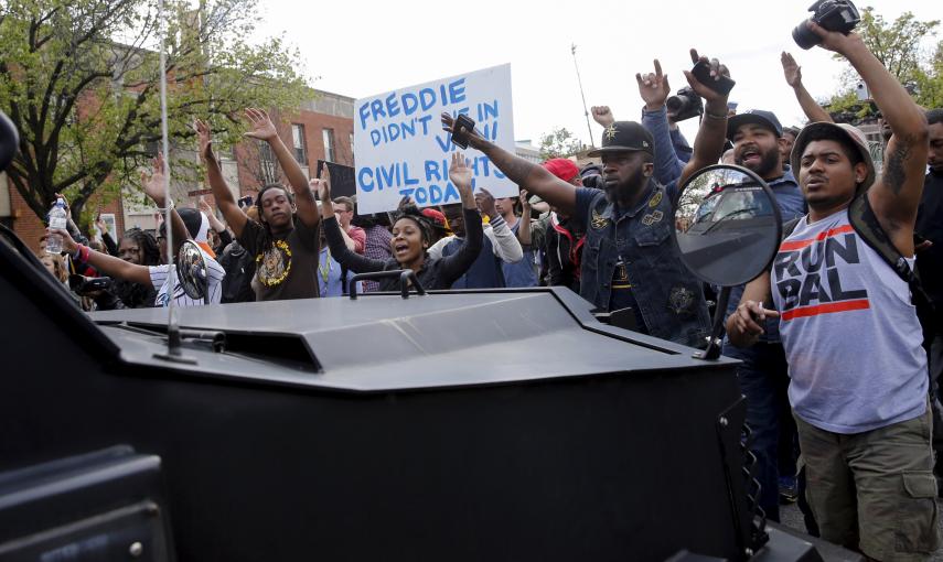 Demonstrators march in front of a Baltimore police vehicle down Pennsylvania Avenue, a day after it was looted and set ablaze in protest for the death of 25-year-old black man Freddie Gray who died in police custody in Baltimore. REUTERS/Shannon Stapleton