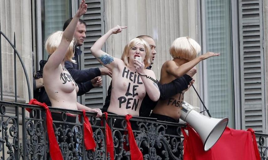 Activistas de organización feminista Femen son evacuadas por agentes de seguridad mientras protestan, a pecho descubierto y con el eslogan: "Le Pen TOP fascist", desde un balcón durante la marcha por el Primero de Mayo organizada por el ultraderechista Fr