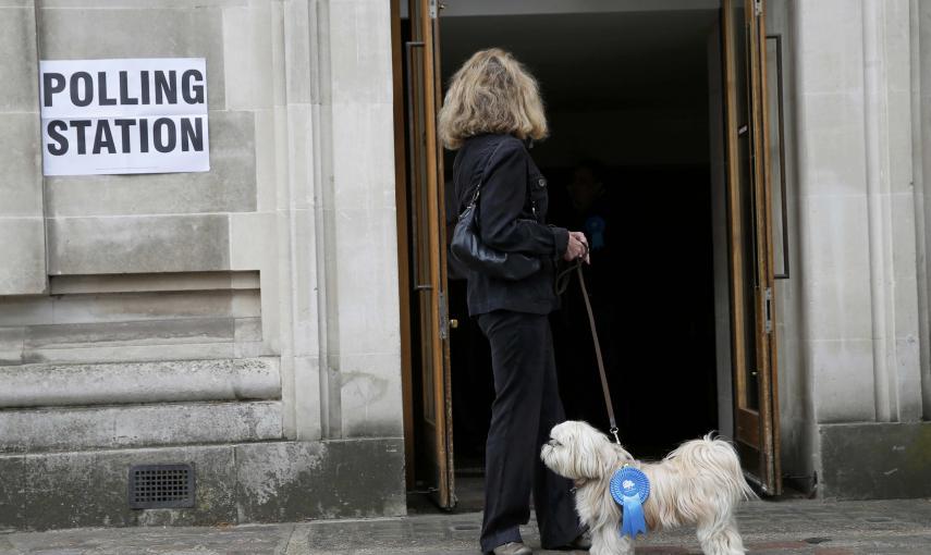Un perro junto a su dueña esperan frente a un colegio electoral para votar. Los británicos votan este jueves para elegir a los 650 miembros del Parlamento y decidir el signo del nuevo Gobierno en unos comicios presididos por la incertidumbre./ REUTERS/ St